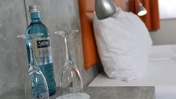 Een minibar met twee flessen Selters en twee glazen op een marmeren oppervlak.