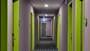 A hallway with doors on both sides, a patterned carpet, and a light fixture on the ceiling.