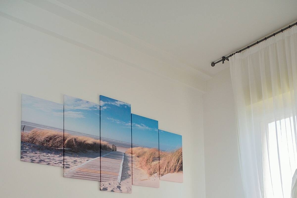 Quarto com cama, mesa de cabeceira e janela com cortinas.