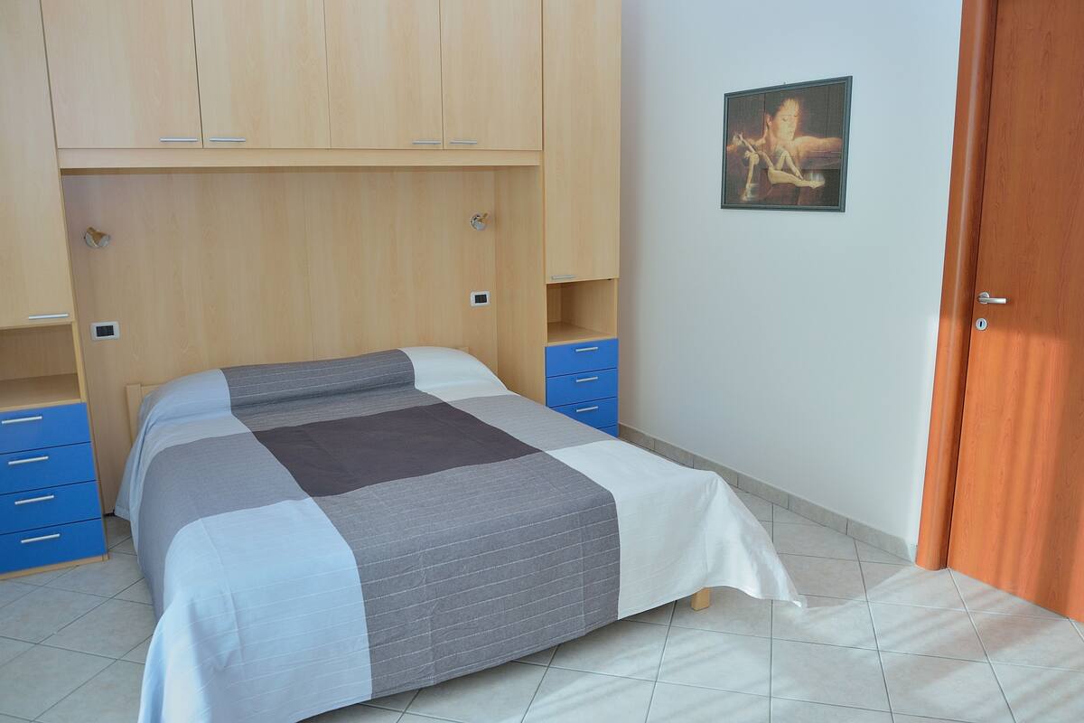 Quarto com cama, guarda-roupa e porta.