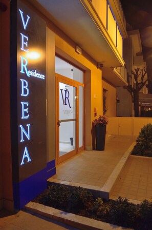 A hotel entrance with illuminated signage reading "VERBENA Residence" and a glass door with a logo. - Residence Verbena (Rimini)