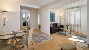 Una sala moderna con una mesa de centro de vidrio, un sofá y un comedor con una mesa y sillas de vidrio.