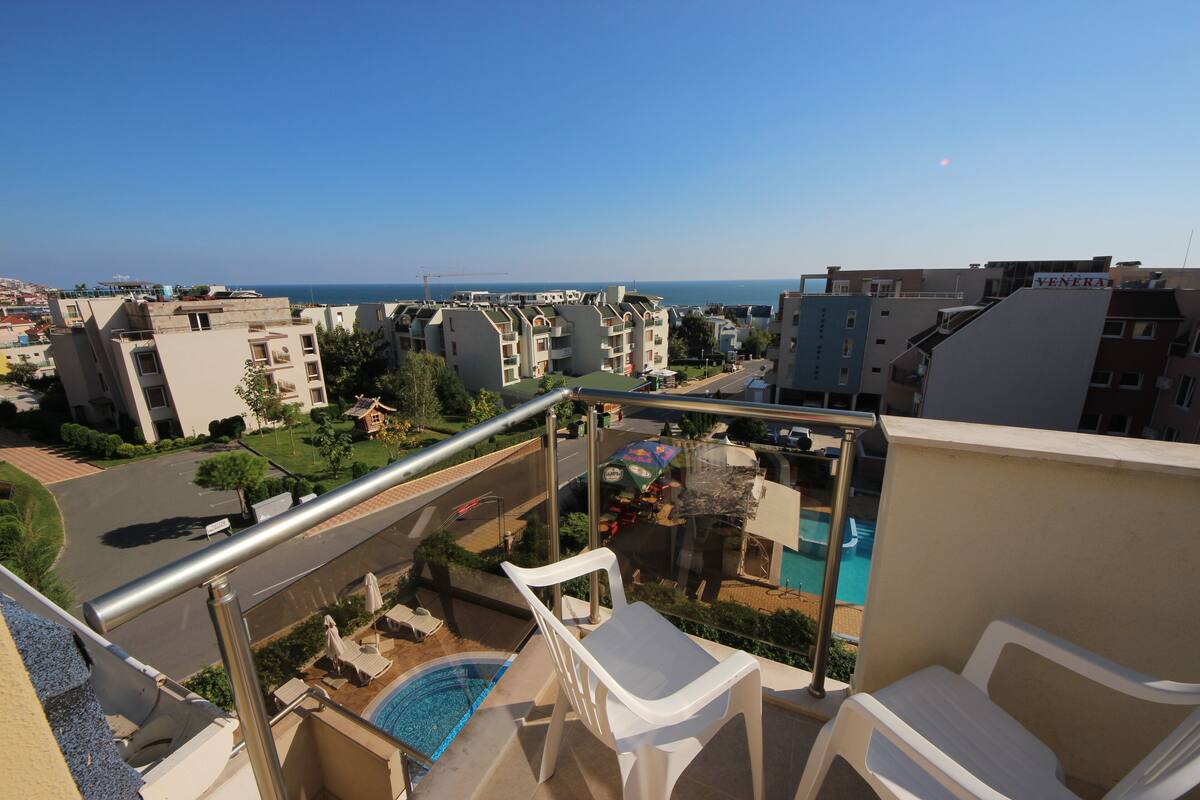 A residential area with a pool, a balcony with chairs, and a view of the sea.