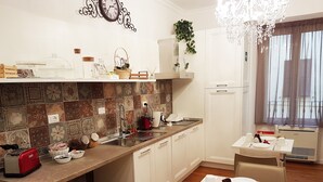 A modern kitchen with a tiled backsplash, a coffee machine, a sink, and a dining area with a table set for two. - MORE Cola di Rienzo B&B (Rome)
