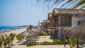 Un hotel a la vora de la platja, amb edificis de teules i una extensa platja de sorra, i una vista clara de l'oceà.