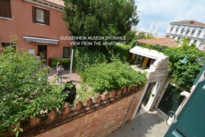 The Guggenheim Museum entrance from an apartment view, featuring a brick wall, greenery, and a white building with a sign. - PEGGY-Guggenheim (Venice)