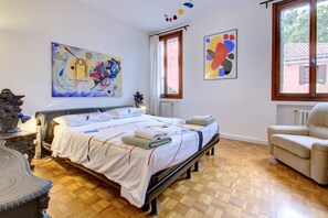 A bedroom with a bed, a chair, and two paintings on the wall. - PEGGY-Guggenheim (Venice)