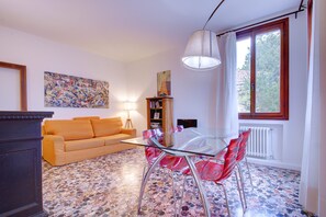 A living room with a glass table and red chairs, a sofa, a bookshelf, and a painting on the wall. - PEGGY-Guggenheim (Venice)