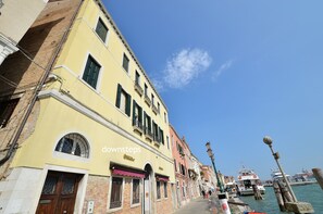 A row of historic buildings with a clear sky and a boat docked at the waterfront. - PATRIZIO panoramic view (Venice)