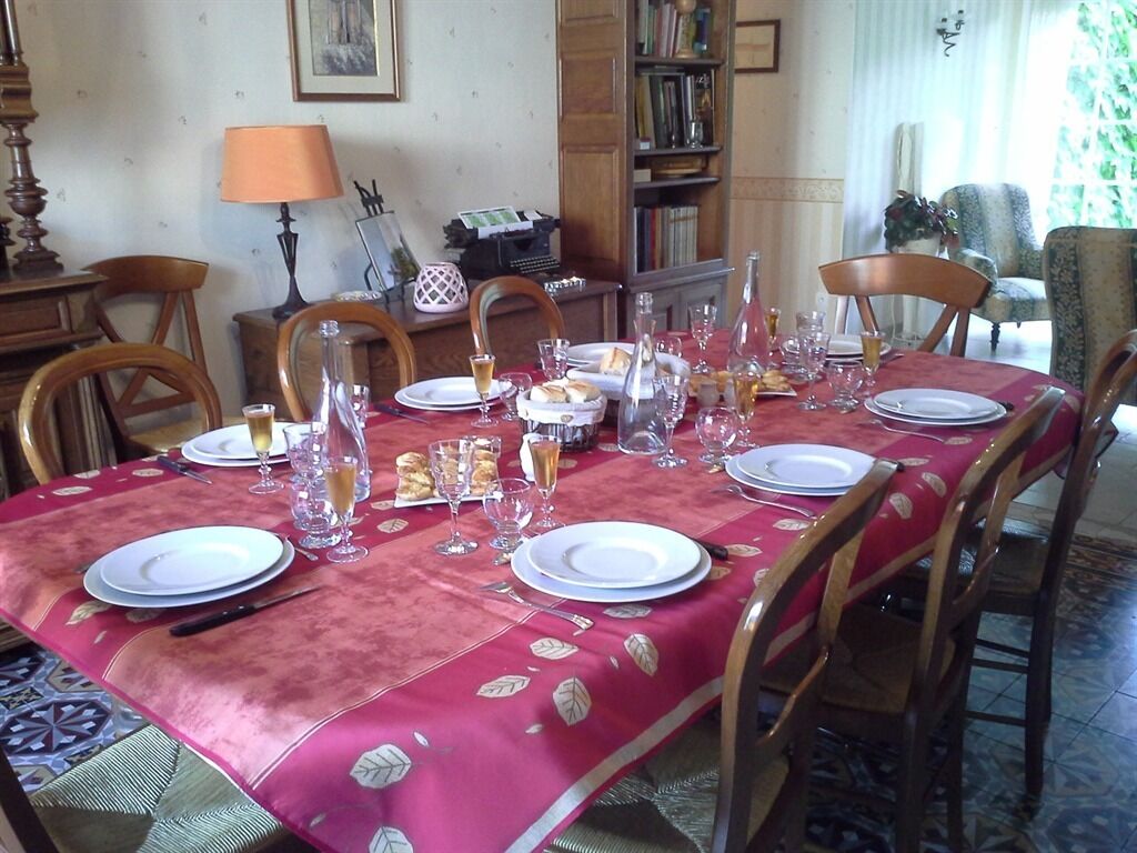 Une table à manger dressée avec des assiettes, des verres et une bouteille, entourée de chaises en bois.