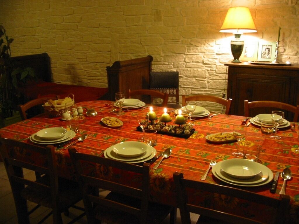 A dining table set for four with plates, cutlery, and candles.
