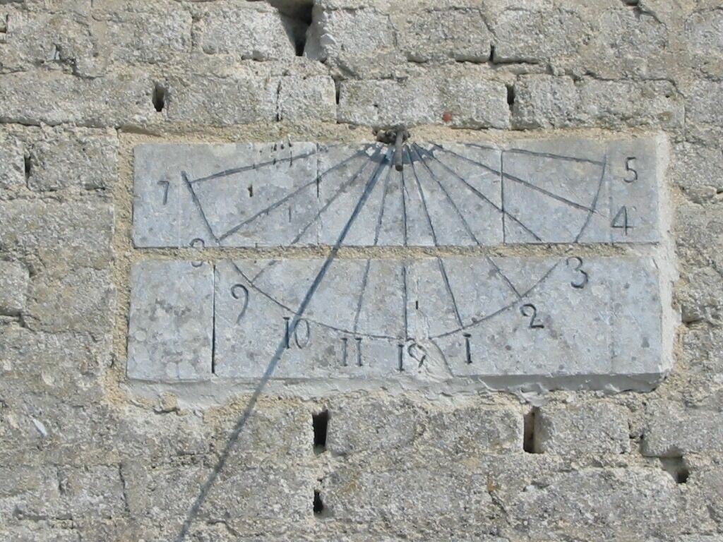 A stone wall with a sundial embedded in it.