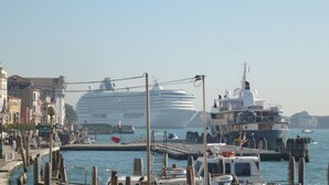 A harbor with a large cruise ship docked, smaller boats, and a pier with buildings in the background. - Cross Canal Set (Venice)