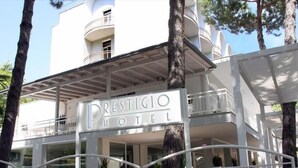 Un hôtel appelé « Prestigio Hotel », doté d’une architecture moderne, avec des balcons et un espace d’entrée abrité.