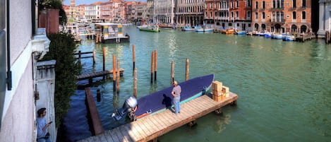A canal with boats docked, a wooden pier, and buildings in the background.