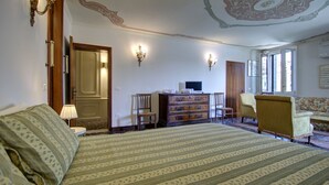 A bedroom with a large bed, a dresser, a chair, and a television. - GRITTI Grand Canal (Venice)