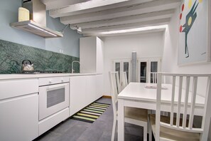 Kompakti keittiö, jossa on valkoiset kaapit, sisäänrakennettu uuni ja kaasuliesi.