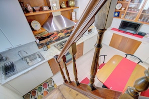 A kitchen with a stainless steel range hood, a sink, and a variety of spices.