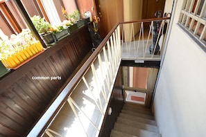A wooden staircase with a metal railing, a bench, and potted plants on the landing.