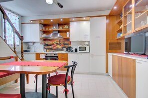Une cuisine moderne avec des meubles en bois, une table à manger avec des chaises et un four à micro-ondes.