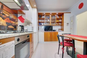 Une cuisine compacte équipée d’une cuisinière, d’un four à micro-ondes et d’un four traditionnel. Un coin repas avec une table et des chaises est également disponible.