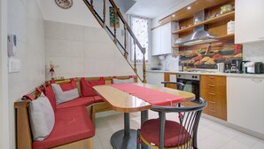Eine Küche mit Essbereich, darunter ein Holztisch, Stühle und eine eingebaute Bank mit Kissen.