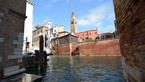 A canal with buildings on either side, a bridge, and a tower in the background.