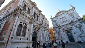 A historic building with classical architecture, large windows, and statues.