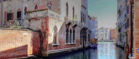 A narrow canal with buildings on either side, featuring arched windows and balconies.