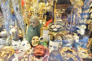 A display of various masks and theatrical props, including a golden mask and a mask with a red nose. - BAROCCO-Veneziano (Venice)