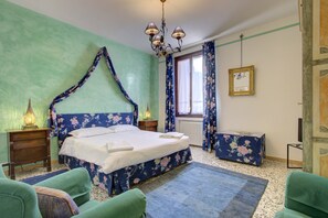 A bedroom with a four-poster bed, a nightstand with a lamp, a dresser, and a window with curtains. - BAROCCO-Veneziano (Venice)