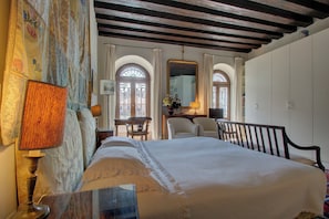 Een slaapkamer met een groot bed, een bureau, twee stoelen en een spiegel.