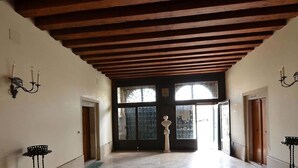 Un pasillo con techo de madera, paredes de piedra y una estatua en el centro.