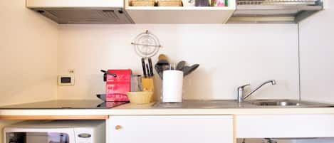 A compact kitchen with a microwave, sink, and various utensils.