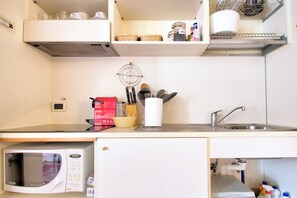 A compact kitchen with a microwave, sink, and various utensils. - TRIBUNO Grand Canal (Venice)
