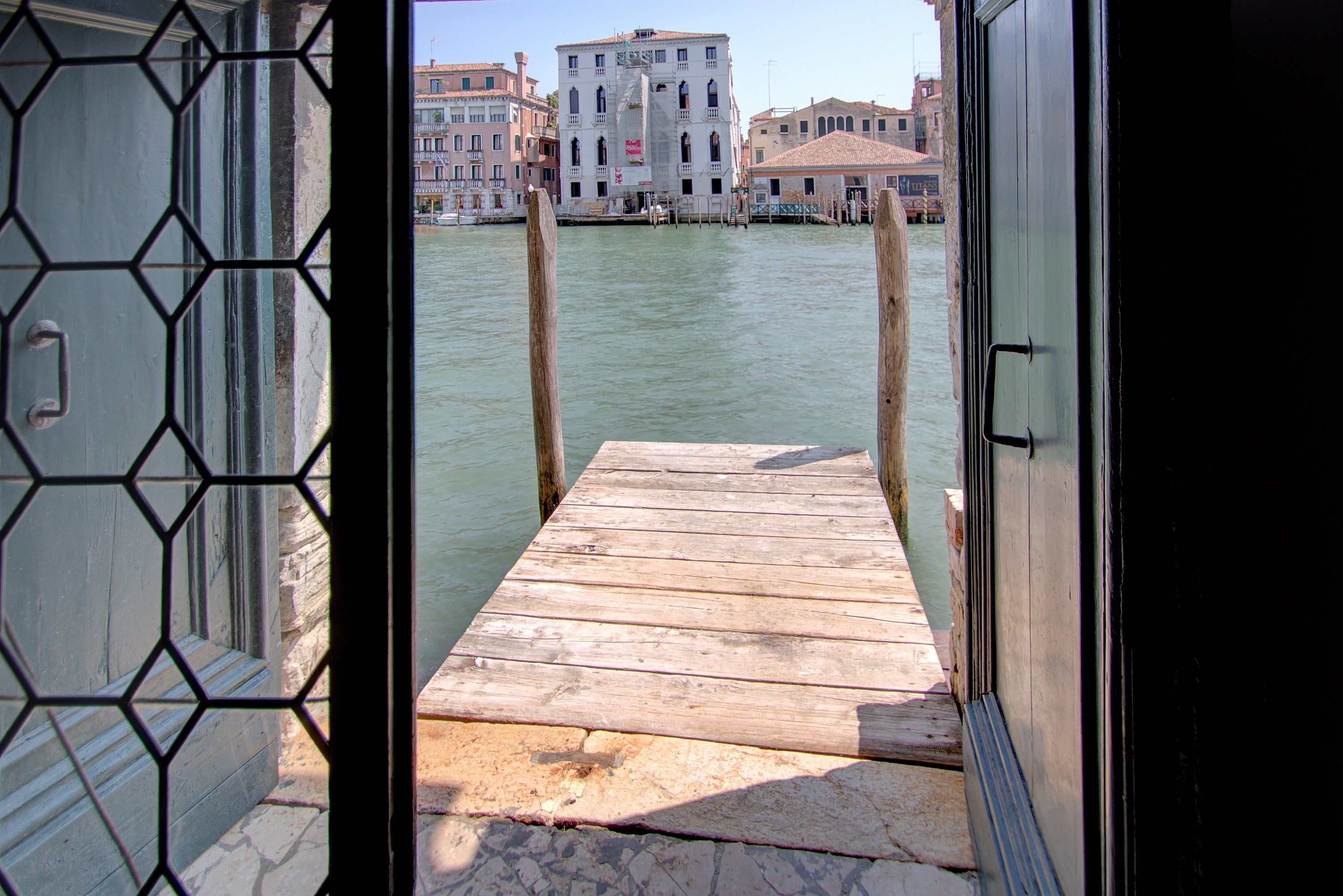 A wooden dock leading to a canal with buildings in the background.
