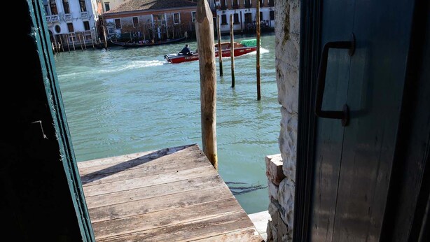 Un muelle de madera que conduce a un muro de piedra con una puerta.
