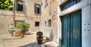 A courtyard with a stone floor, a green door, and a potted plant. - TRIBUNO Grand Canal (Venice)