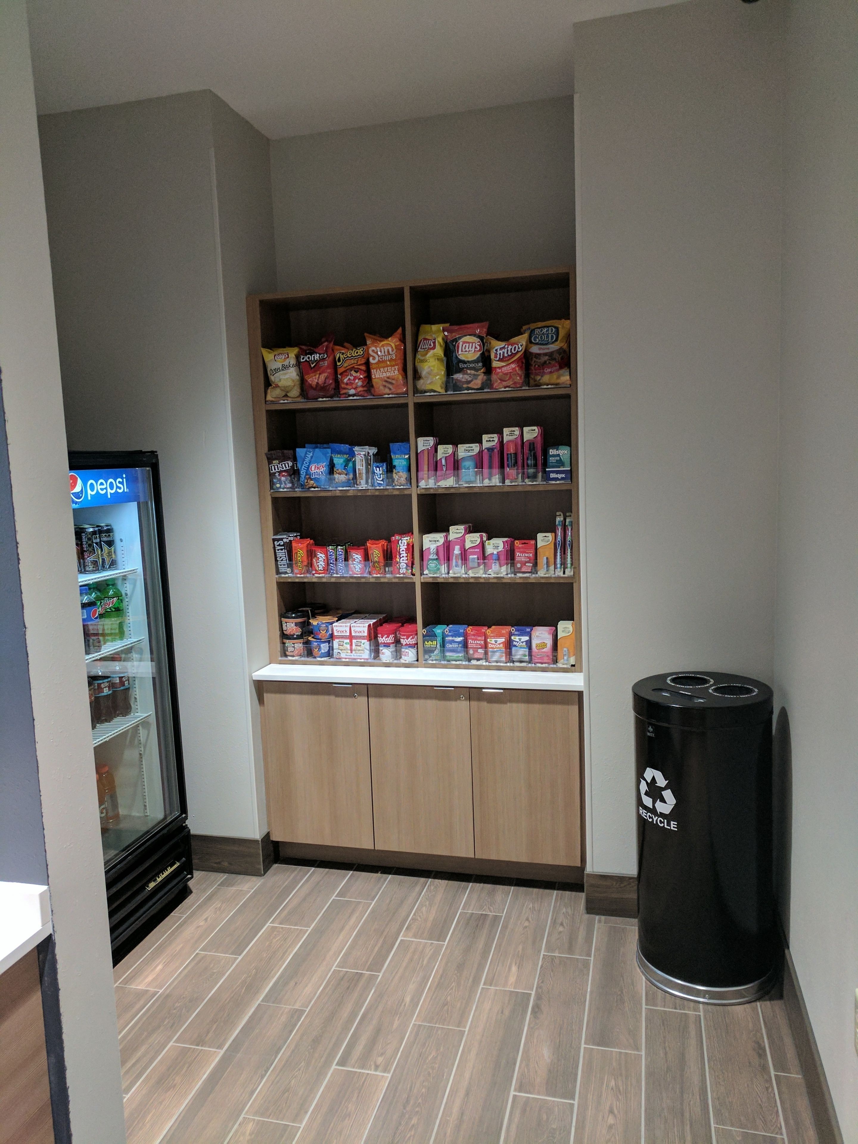 A snack and beverage vending area with a Pepsi refrigerator and a recycling bin.