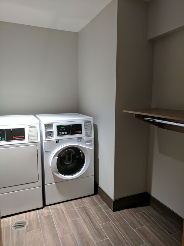 A laundry room with two stacked washing machines and a shelf above.