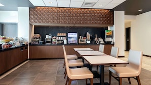 Un restaurante moderno con mostrador, zona de estar y diferentes estaciones de comida y bebida.