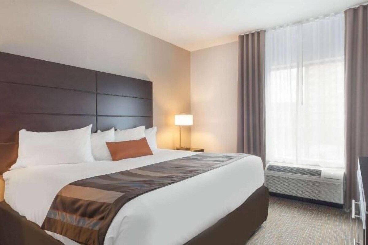 Una habitación de hotel con una cama grande, un escritorio, una lámpara y un televisor.