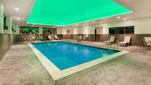 Una piscina con techo de neón verde, rodeada de sillones de descanso y suelo de baldosas.