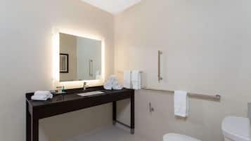A modern bathroom with a dark vanity, a large mirror, and a white toilet.