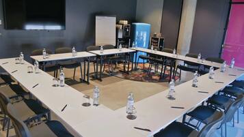 Ein Konferenzraum mit langen Tischen, Stühlen, Wasserflaschen und einer Whiteboard-Tafel.