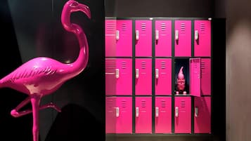 Une sculpture de flamant rose se trouve à côté d’une rangée de casiers roses, et une petite statue est placée à l’intérieur de l’un d’eux.
