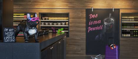 A modern bar area with a dog statue, a neon sign, and a poster.