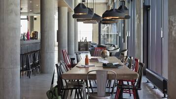 A modern dining area with a long table, chairs, and pendant lights.