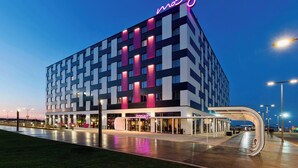 Un hotel moderno con una fachada geométrica llamativa y un letrero de neón destacado.