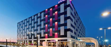 A modern hotel with a distinctive geometric facade and a prominent neon sign.